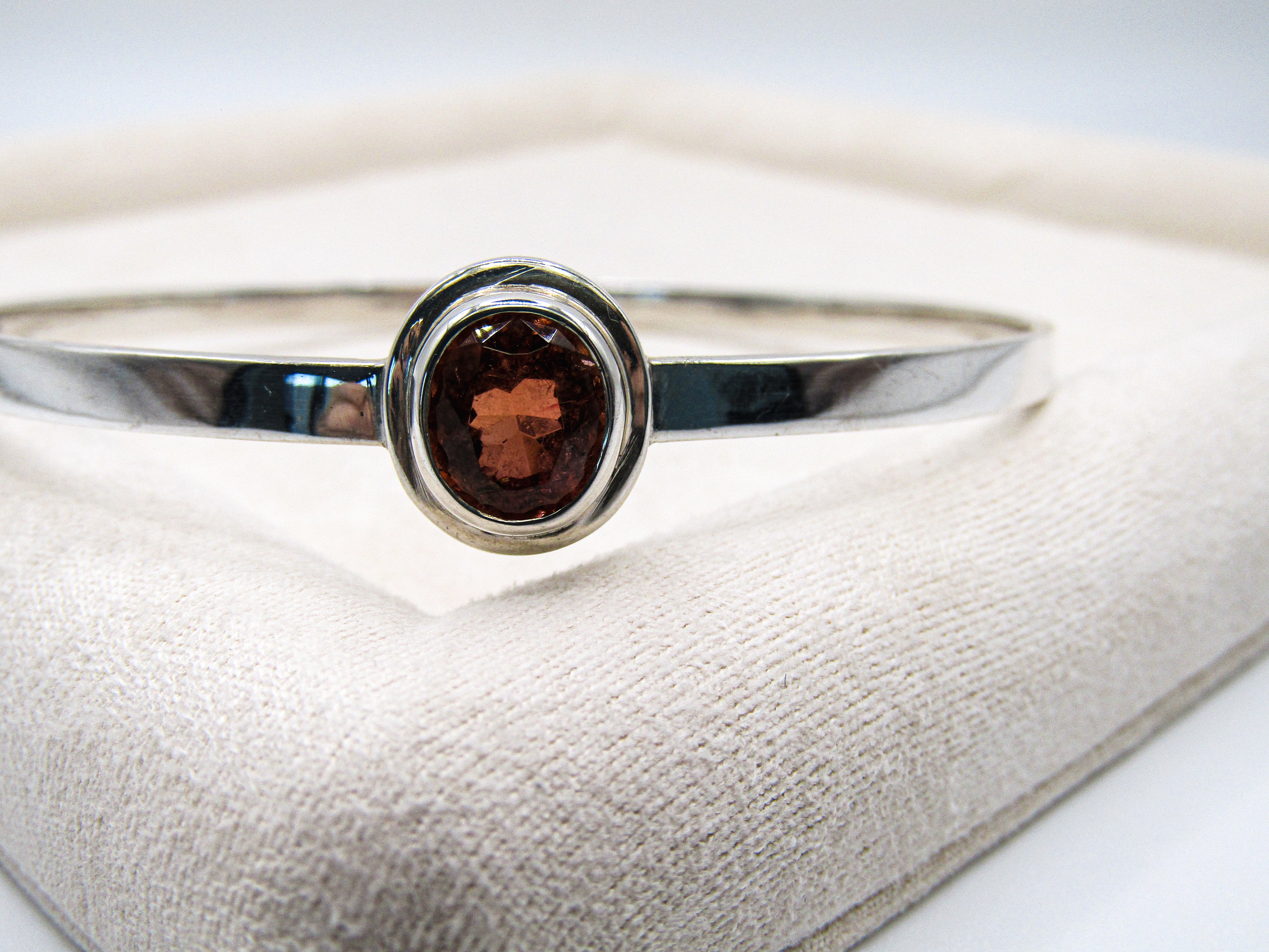 Silver ring with a brown gemstone on a white cushion