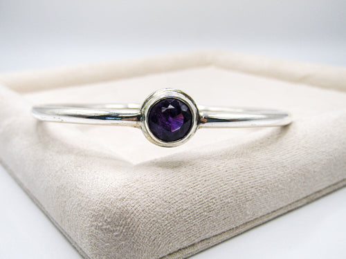 Silver bracelet with a purple gemstone on a white surface