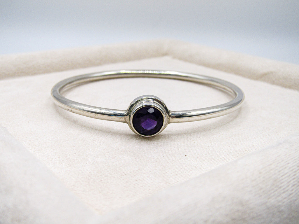Silver ring with a purple gemstone on a white background