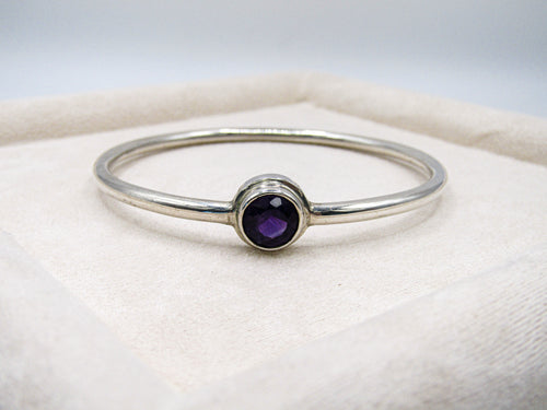 Silver ring with a purple gemstone on a white background