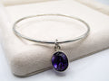Silver bracelet with a purple gemstone on a white surface
