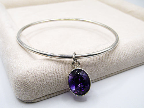 Silver bracelet with a purple gemstone on a white surface