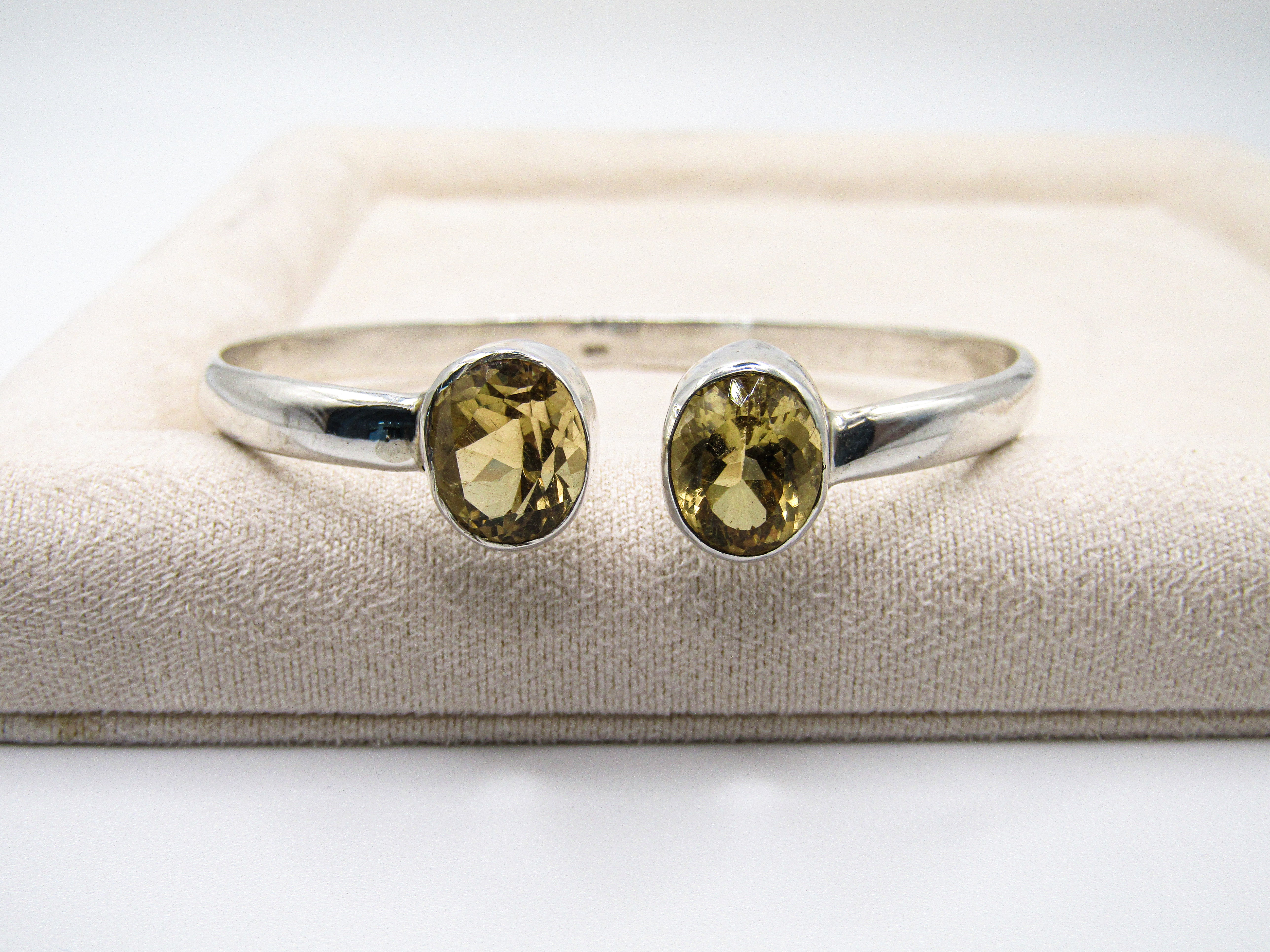 Silver ring with two yellow gemstones on a textured surface