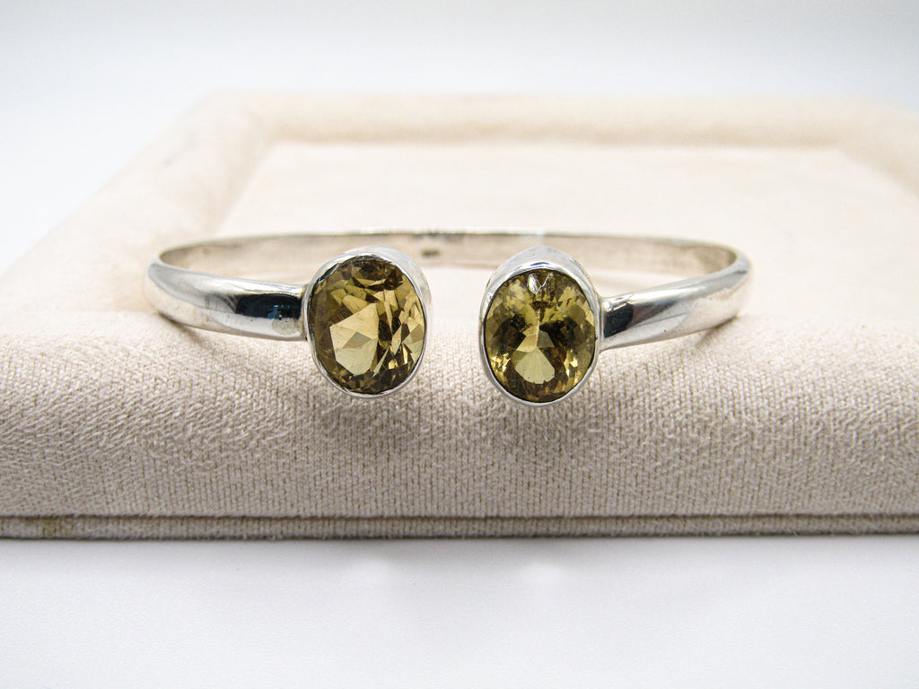 Silver ring with two yellow gemstones on a textured surface