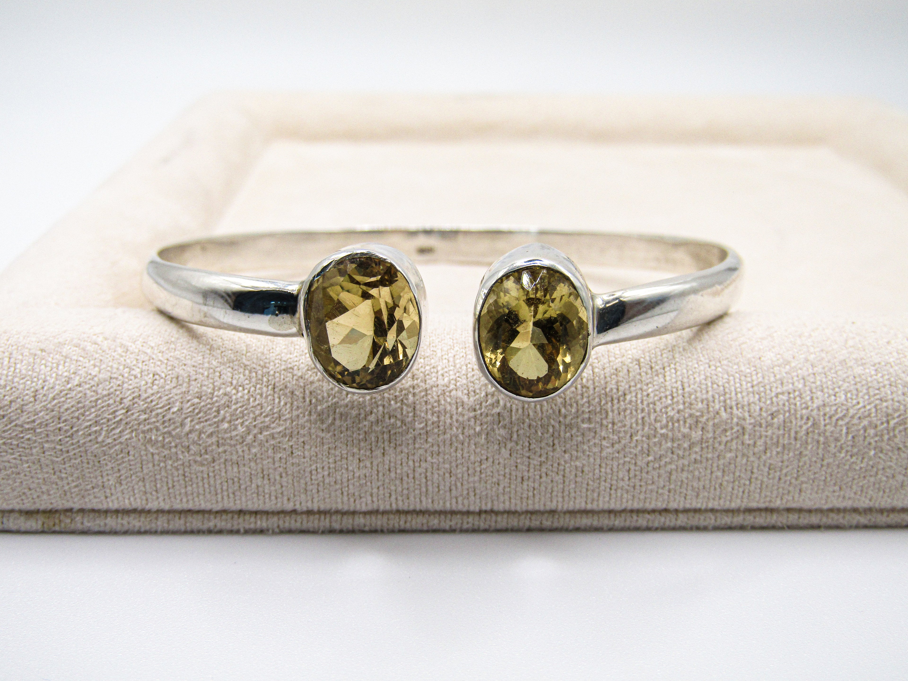 Silver ring with two yellow gemstones on a textured surface
