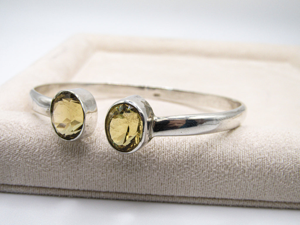 Silver bracelet with two yellow gemstones on a white background