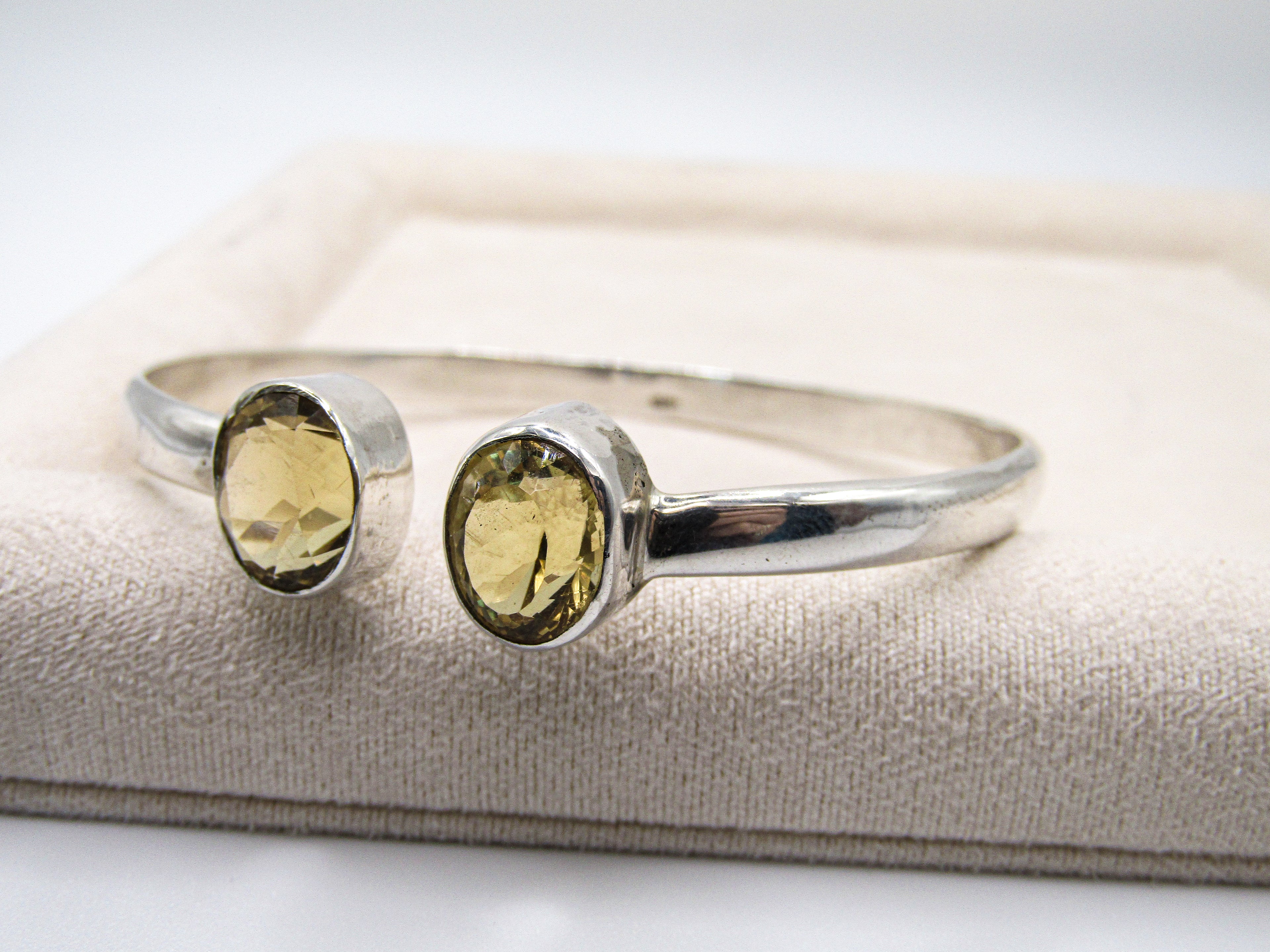 Silver bracelet with two yellow gemstones on a white background