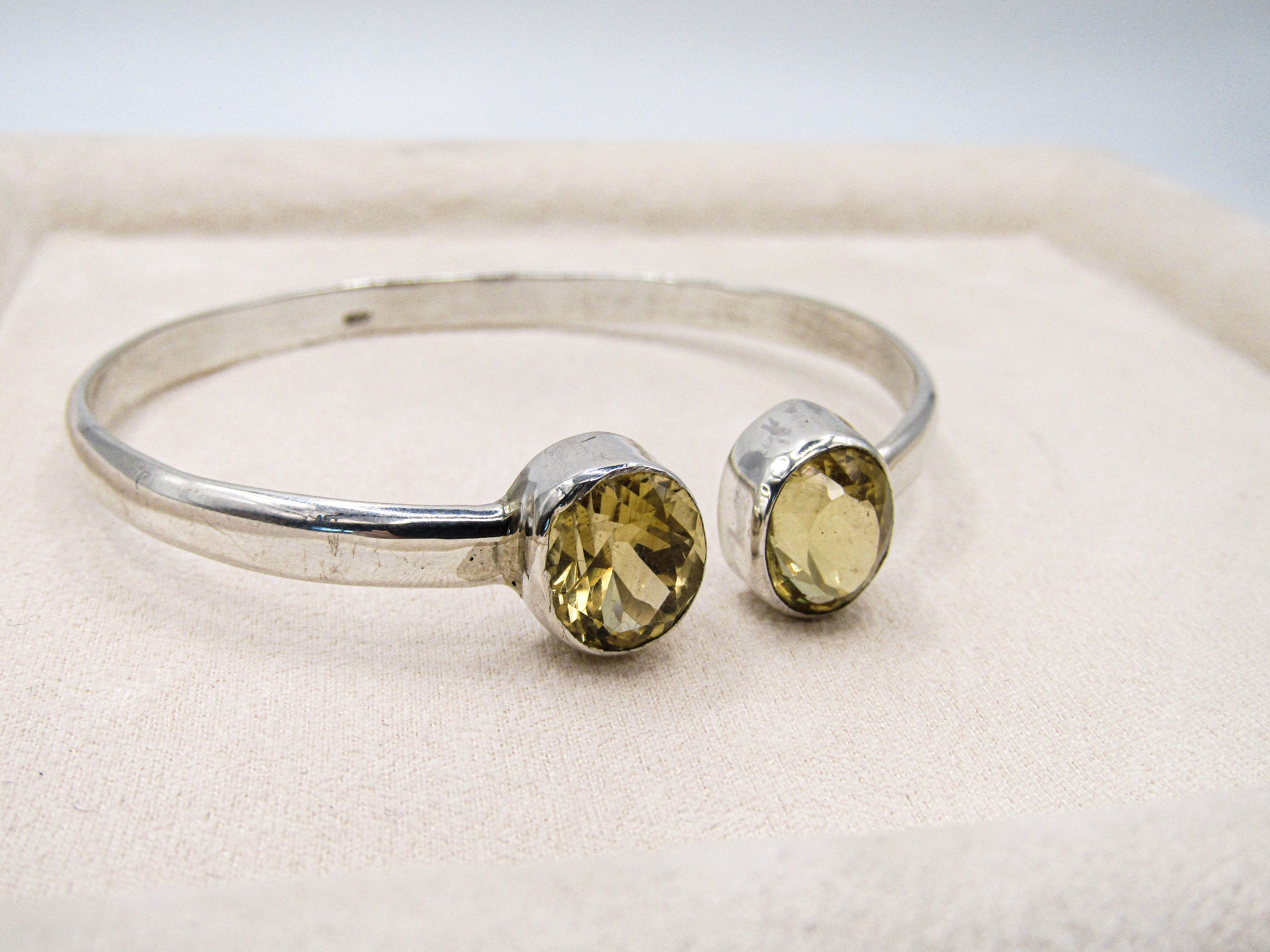 Silver bracelet with yellow gemstones on a light background