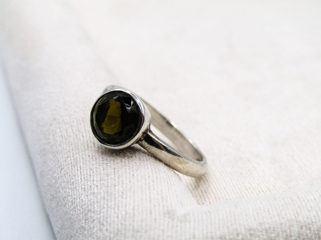 Silver ring with a dark gemstone on a white fabric background