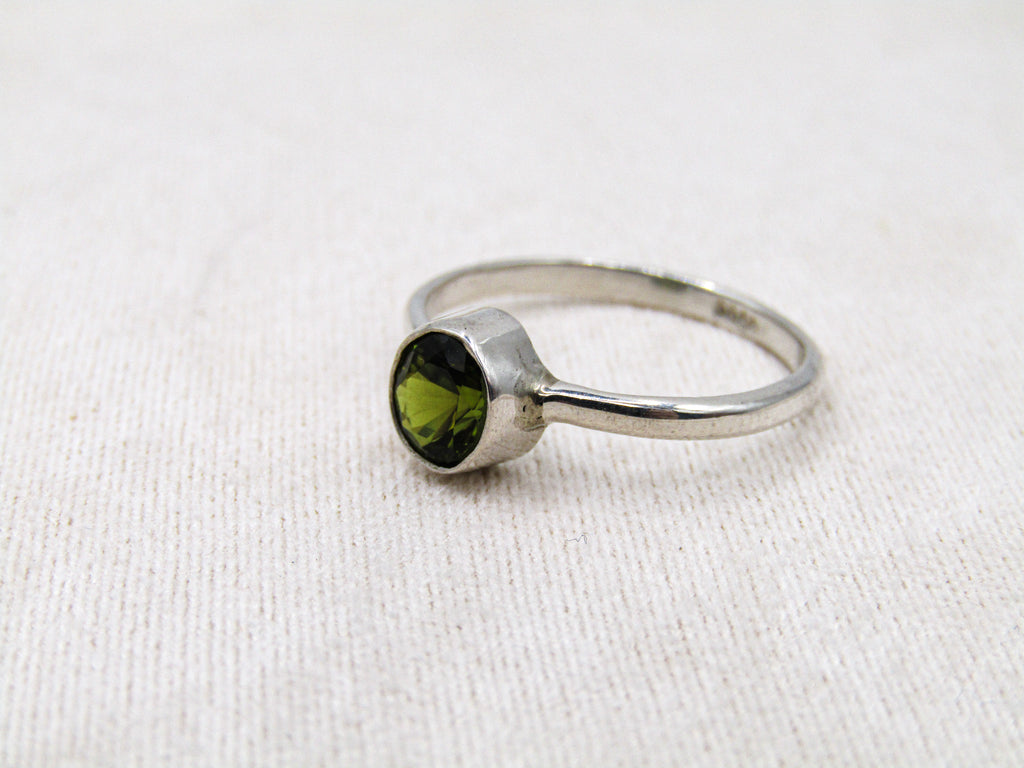 Silver ring with a green gemstone on a white fabric background