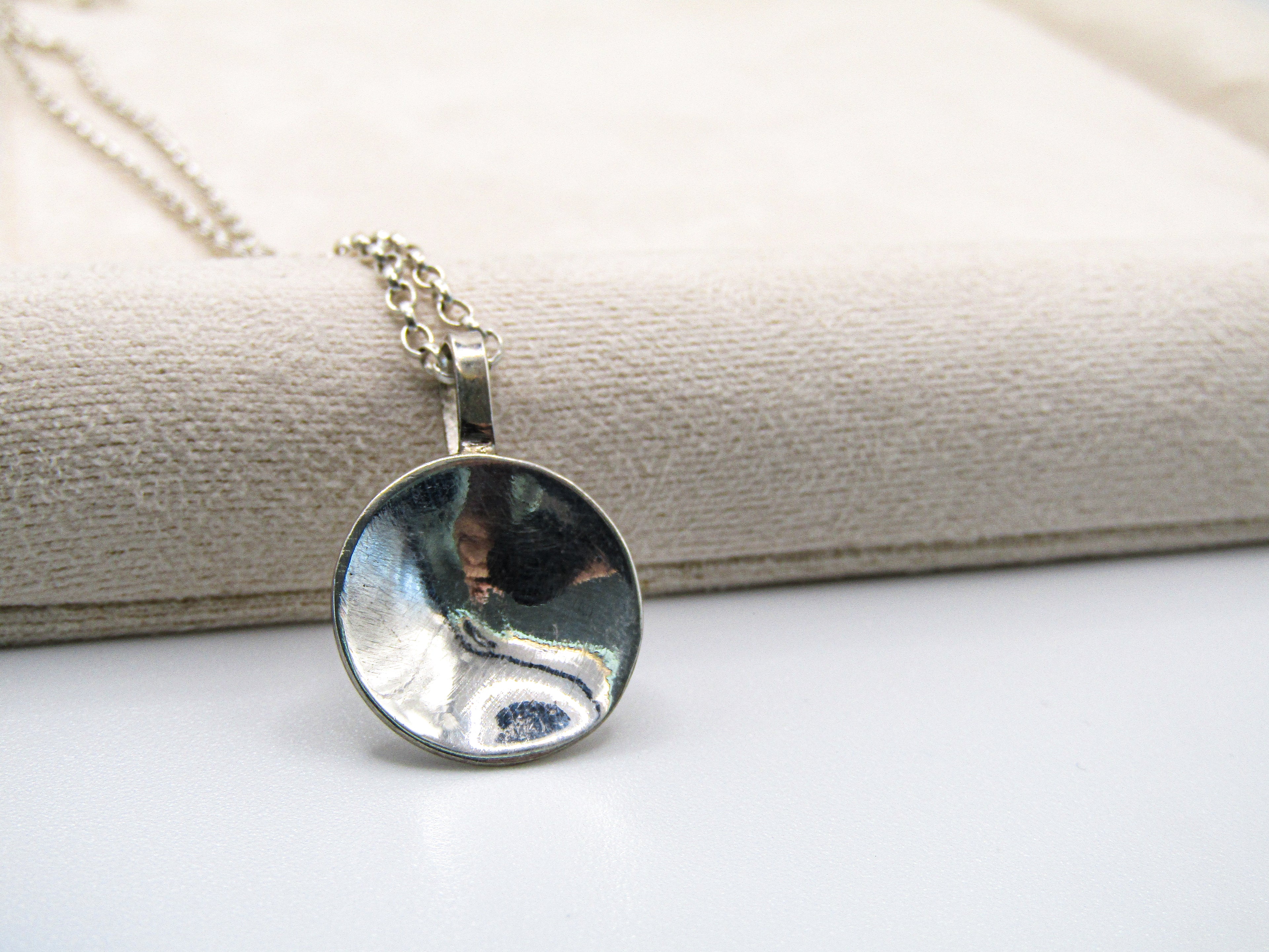 Silver pendant necklace on a textured surface