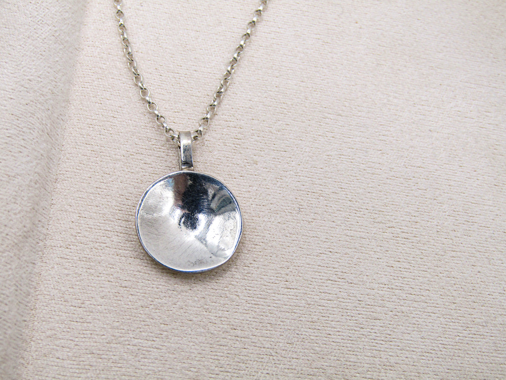 Silver pendant necklace on a beige fabric background