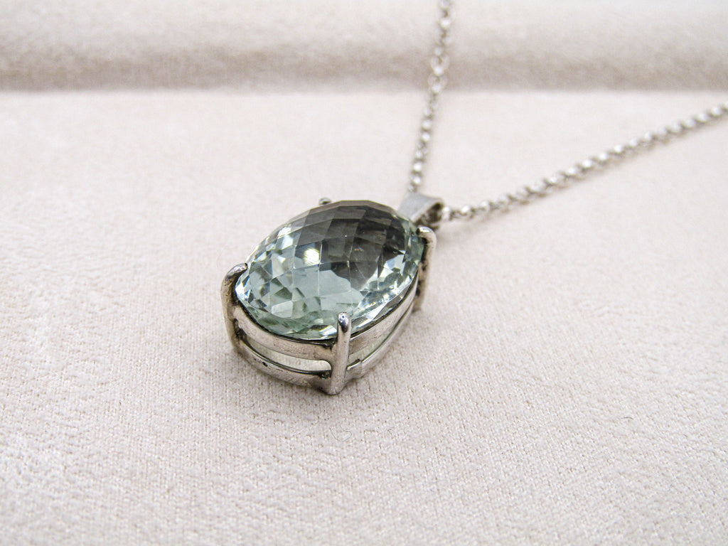 Necklace with a green gemstone pendant on a light beige background