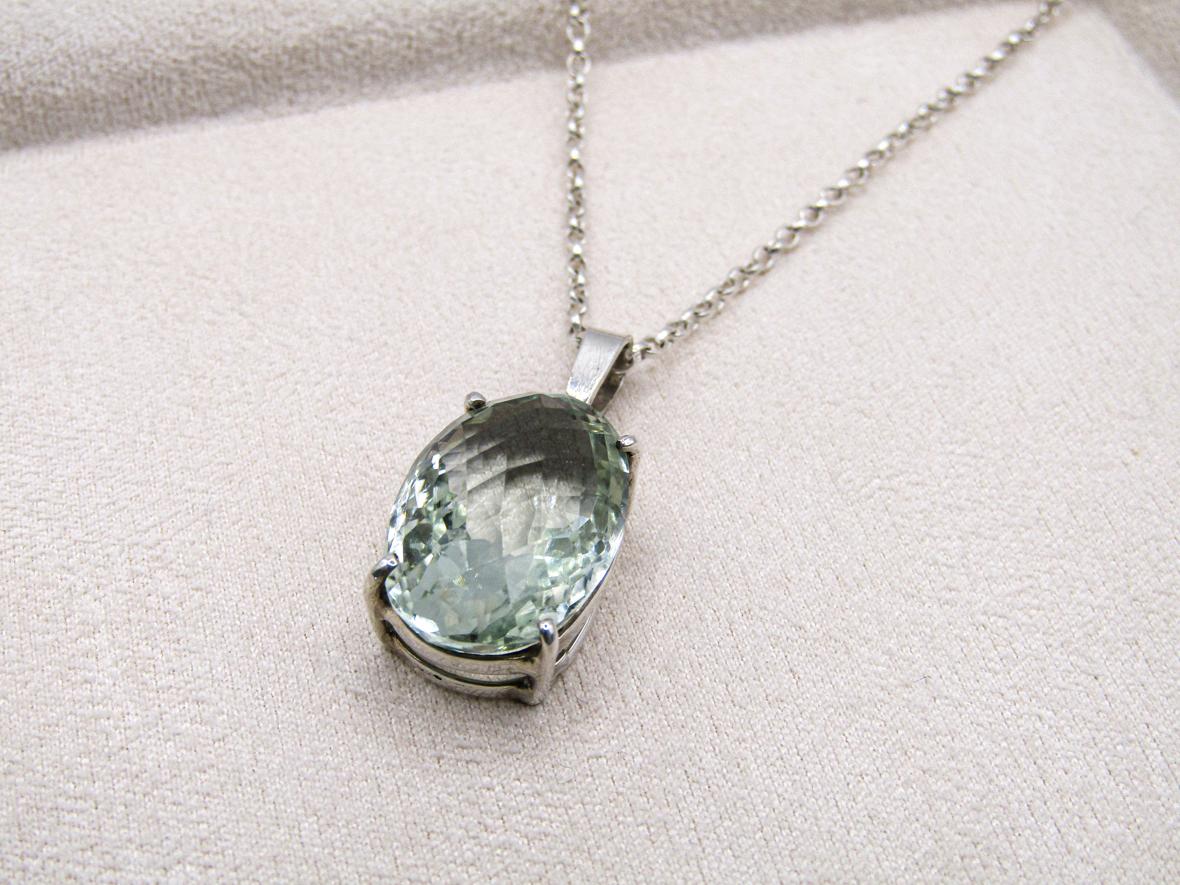 Necklace with a green gemstone pendant on a light gray background