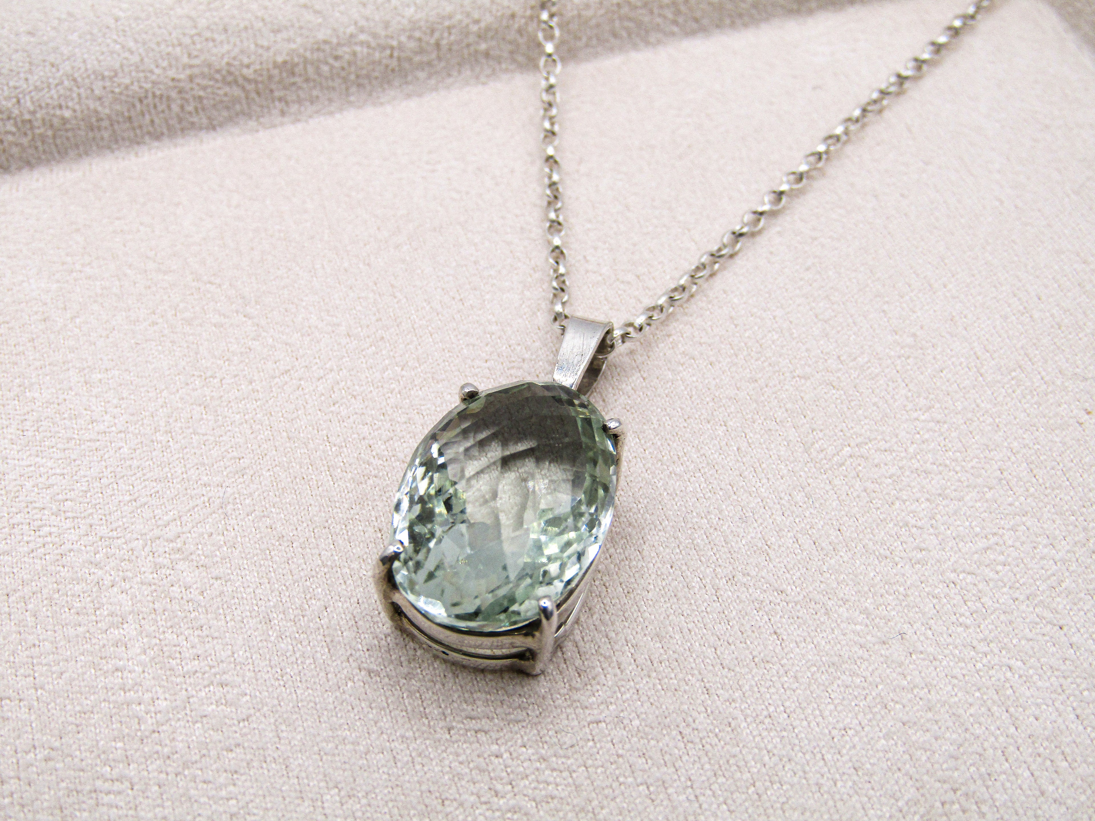 Necklace with a green gemstone pendant on a beige fabric background