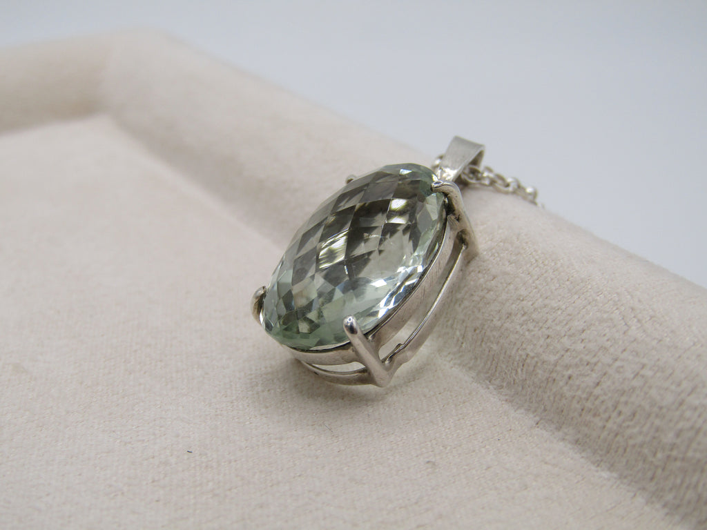 Silver ring with a green gemstone on a beige surface