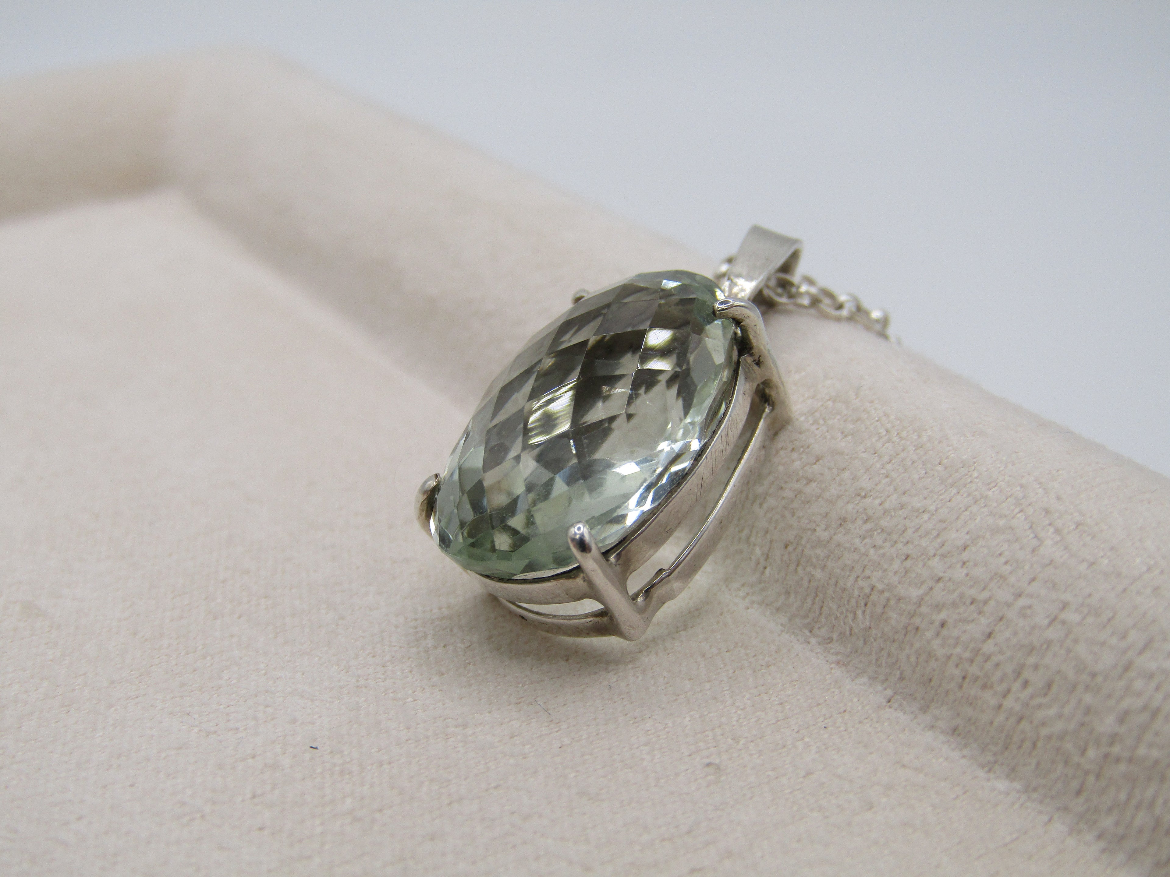 Silver ring with a green gemstone on a beige surface