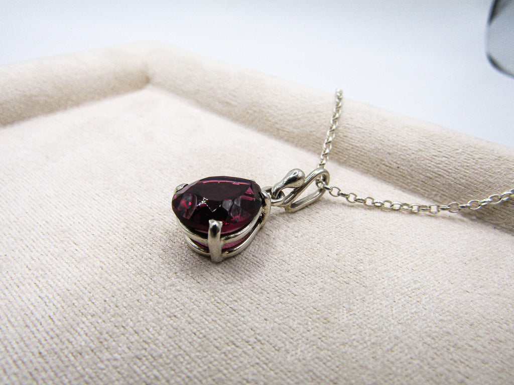 Necklace with a heart-shaped red gemstone pendant on a white fabric background