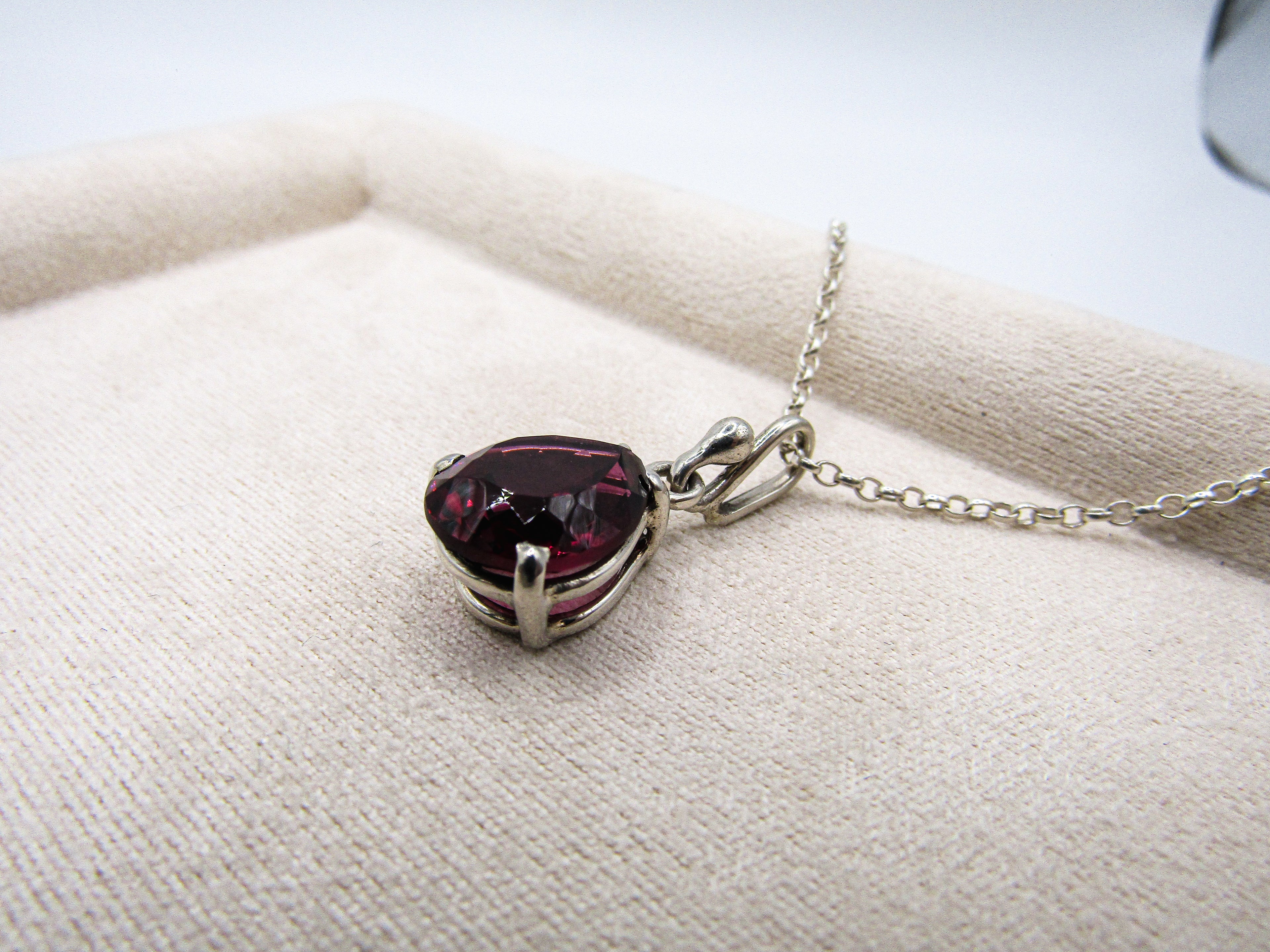 Necklace with a heart-shaped red gemstone pendant on a white fabric background