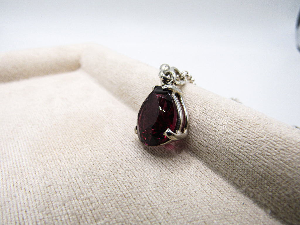 Teardrop-shaped gemstone pendant on a white cushion