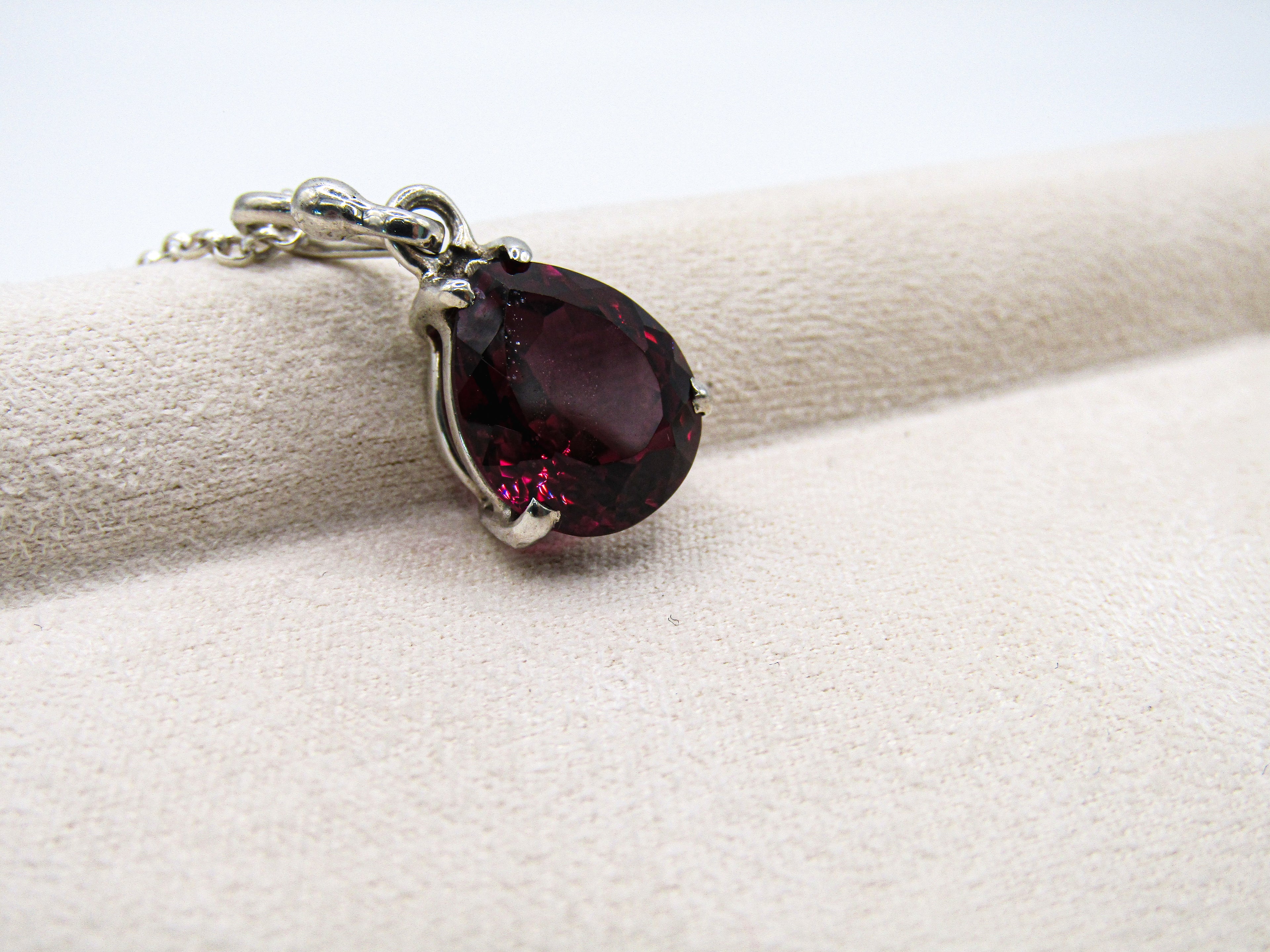 Teardrop-shaped gemstone pendant on a white fabric background