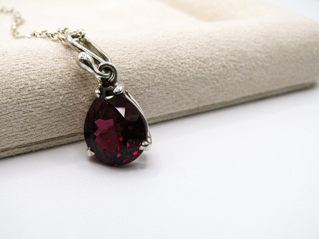Teardrop-shaped red gemstone necklace on a white surface