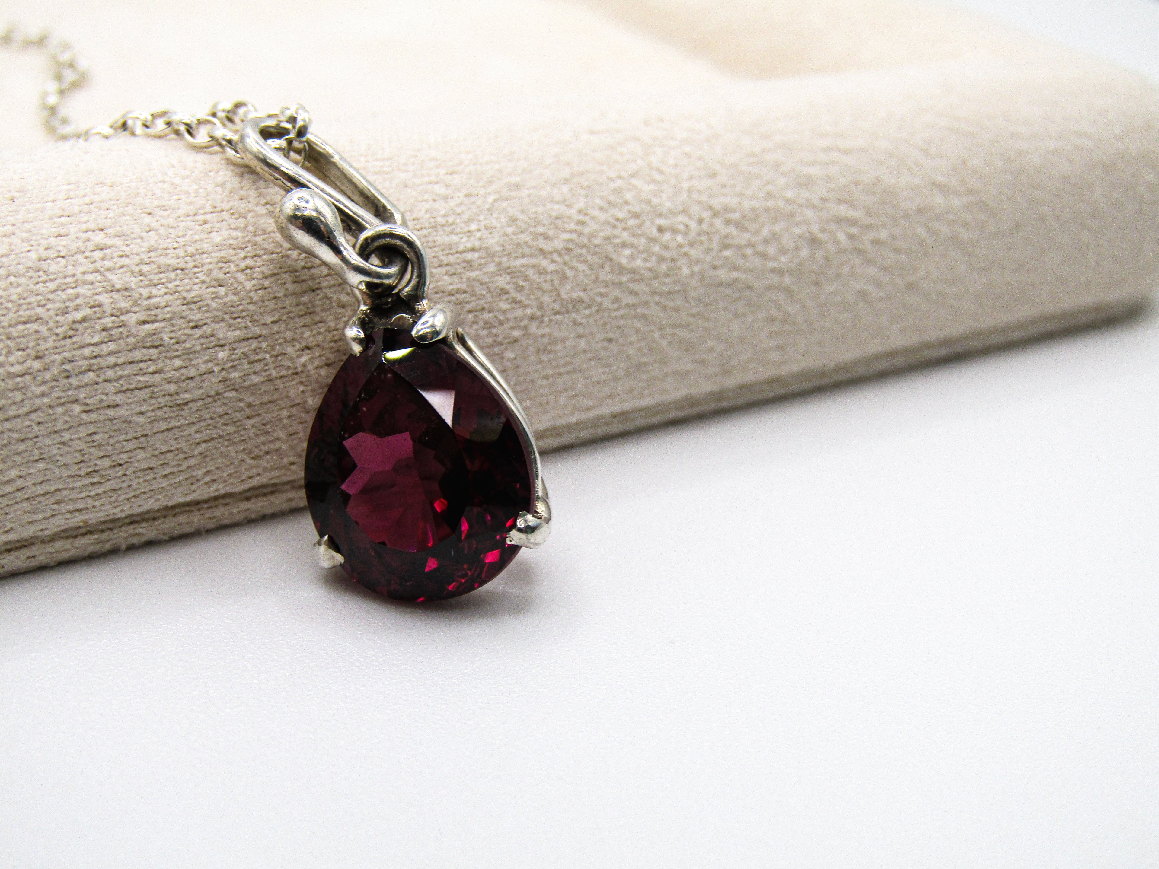 Teardrop-shaped red gemstone necklace on a white surface
