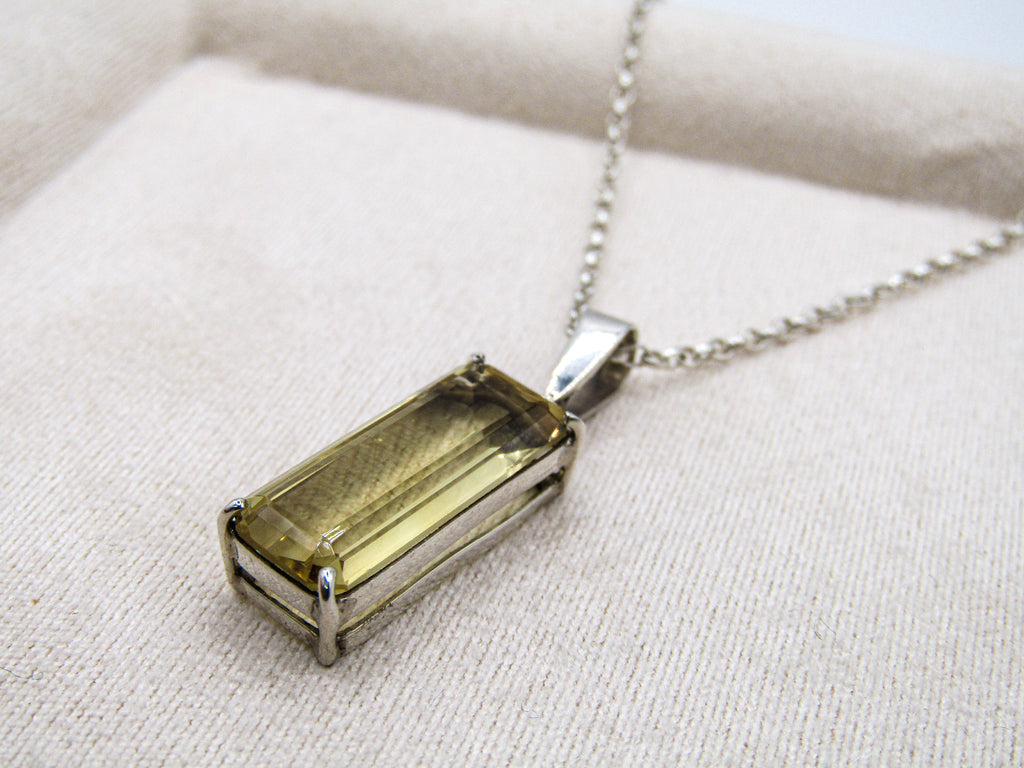 Necklace with a rectangular pendant on a beige fabric background