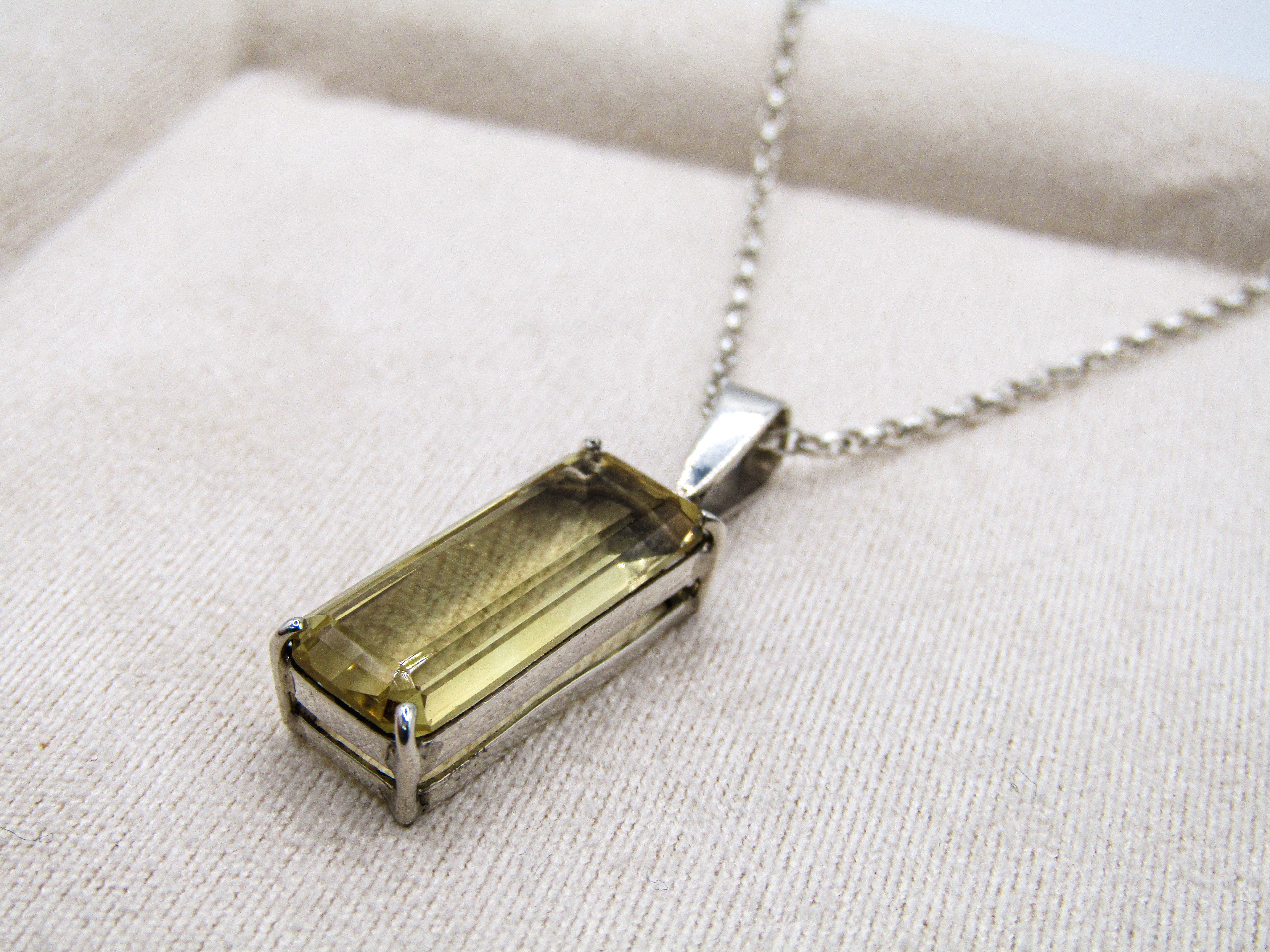 Necklace with a rectangular pendant on a beige fabric background