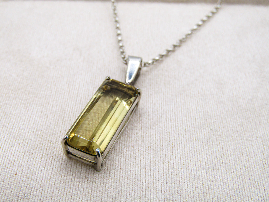 Necklace with a rectangular green gemstone pendant on a light fabric background