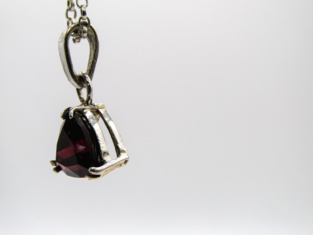 Silver pendant with a red gemstone on a white background