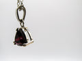 Silver pendant with a red gemstone on a white background