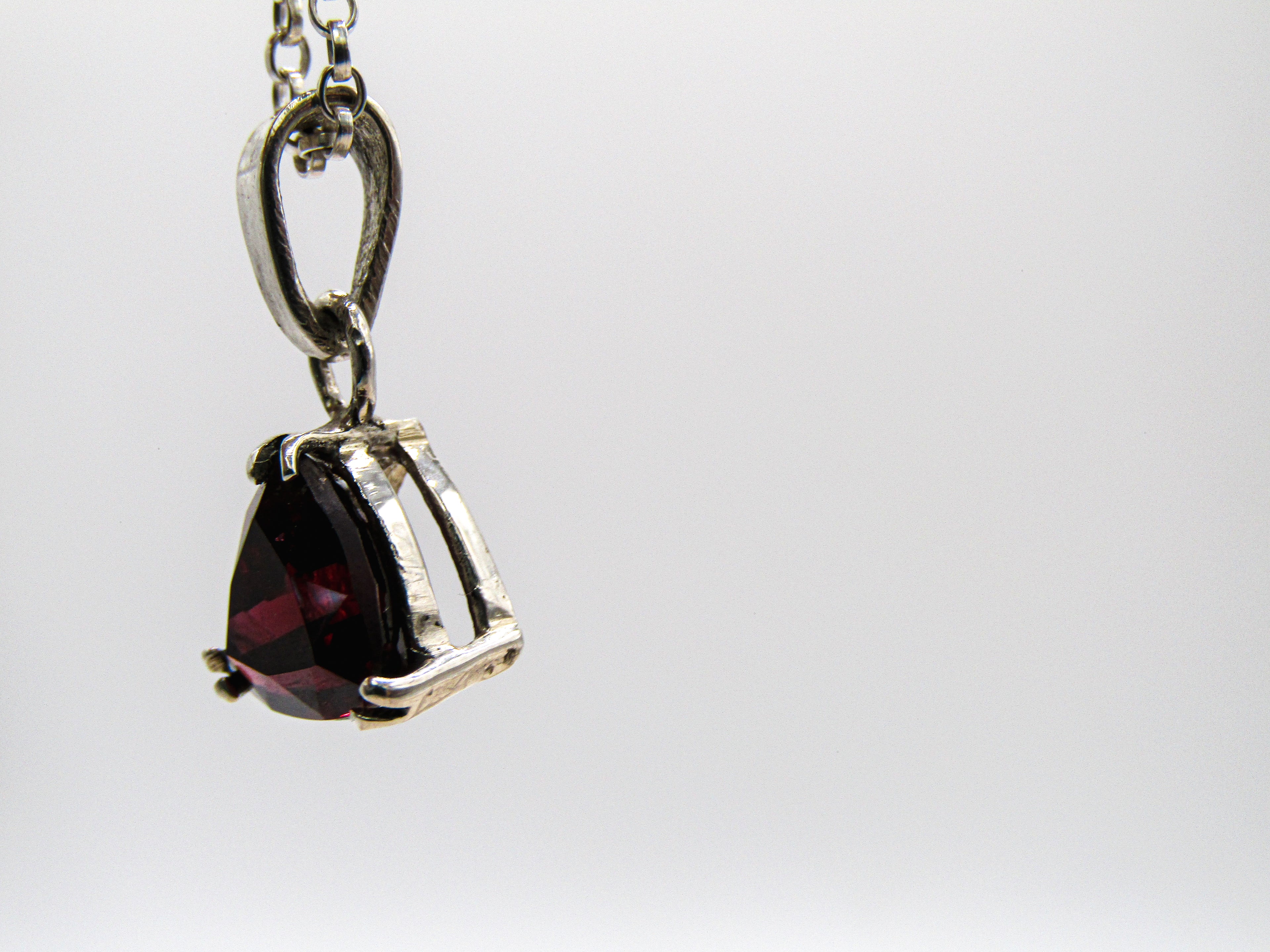 Silver pendant with a red gemstone on a white background