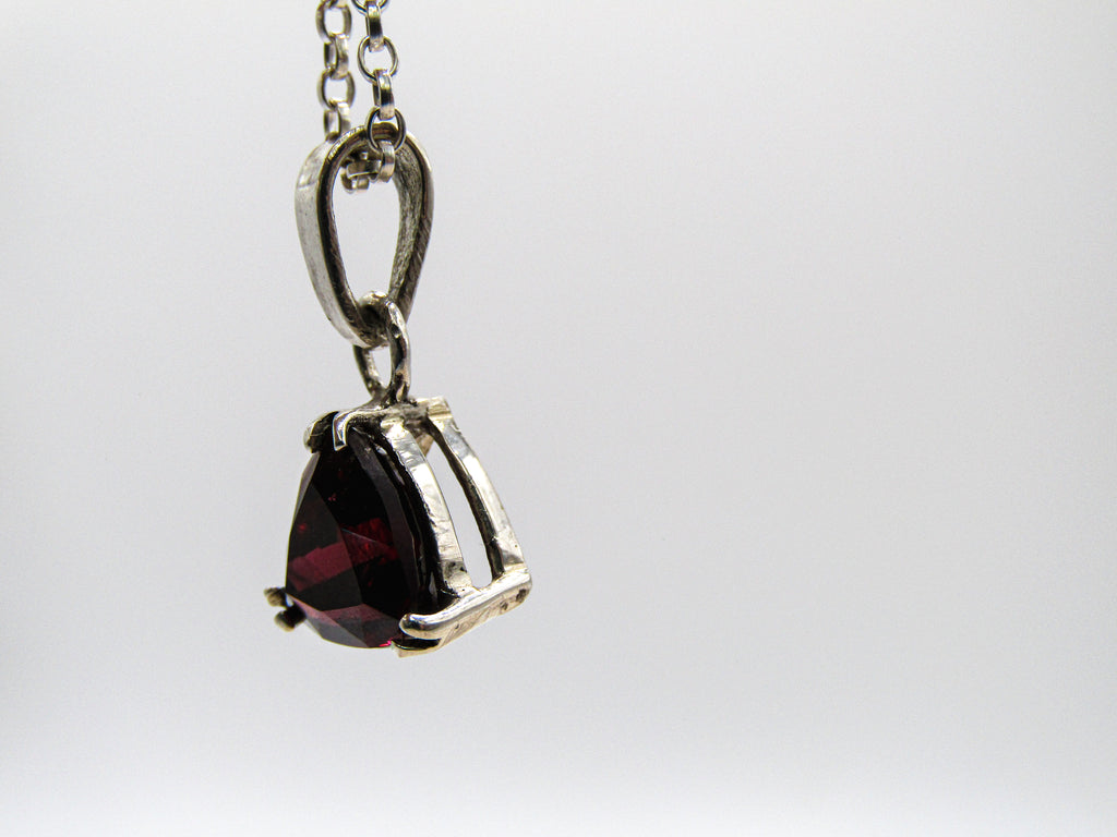 Silver pendant with a red gemstone on a white background