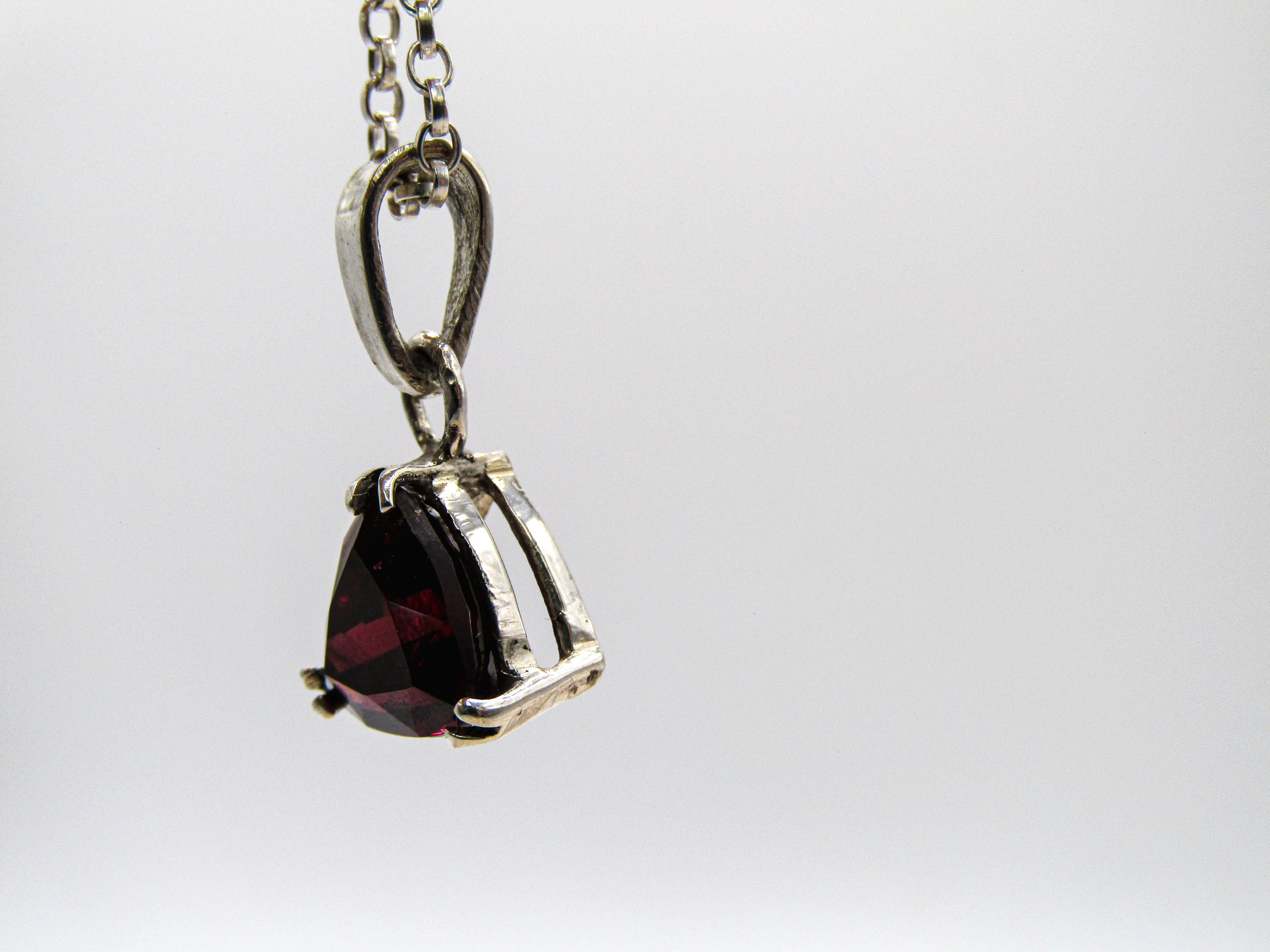 Silver pendant with a red gemstone on a white background