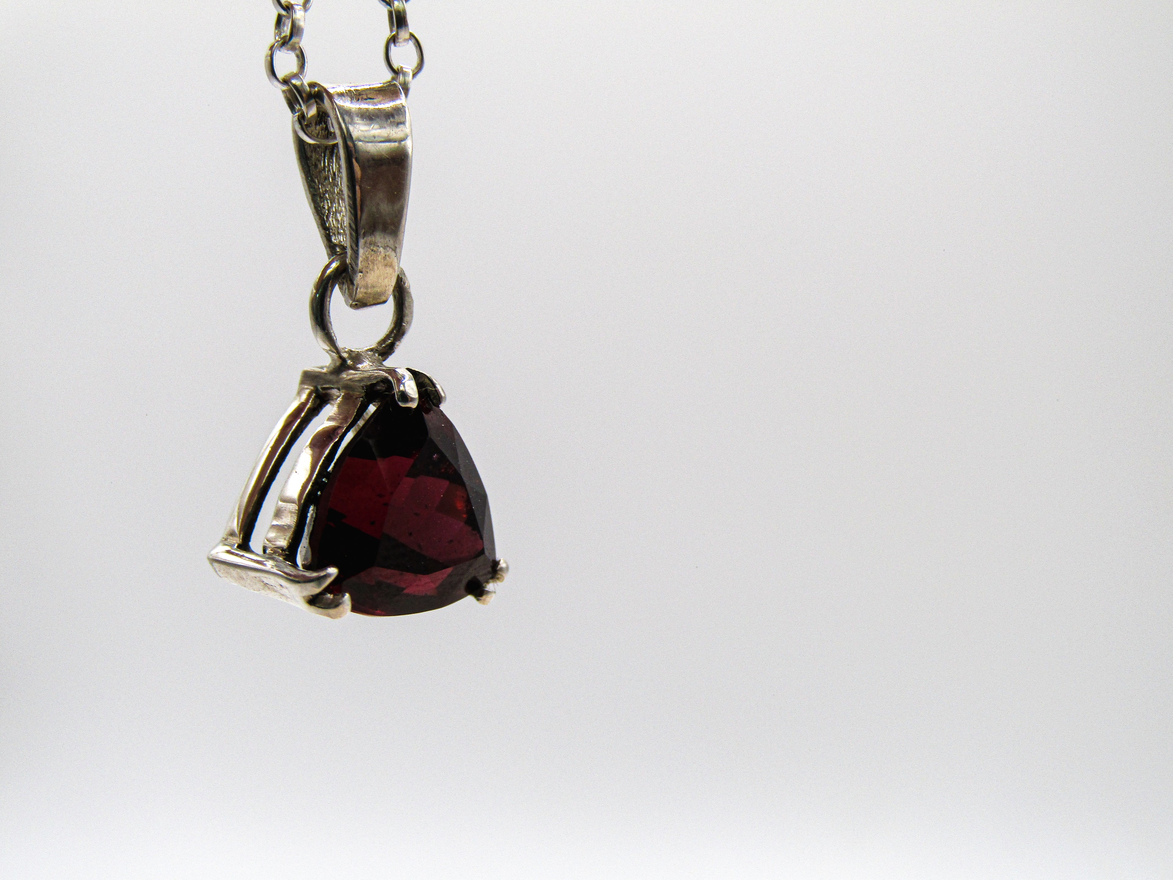 Silver pendant with a red gemstone on a white background