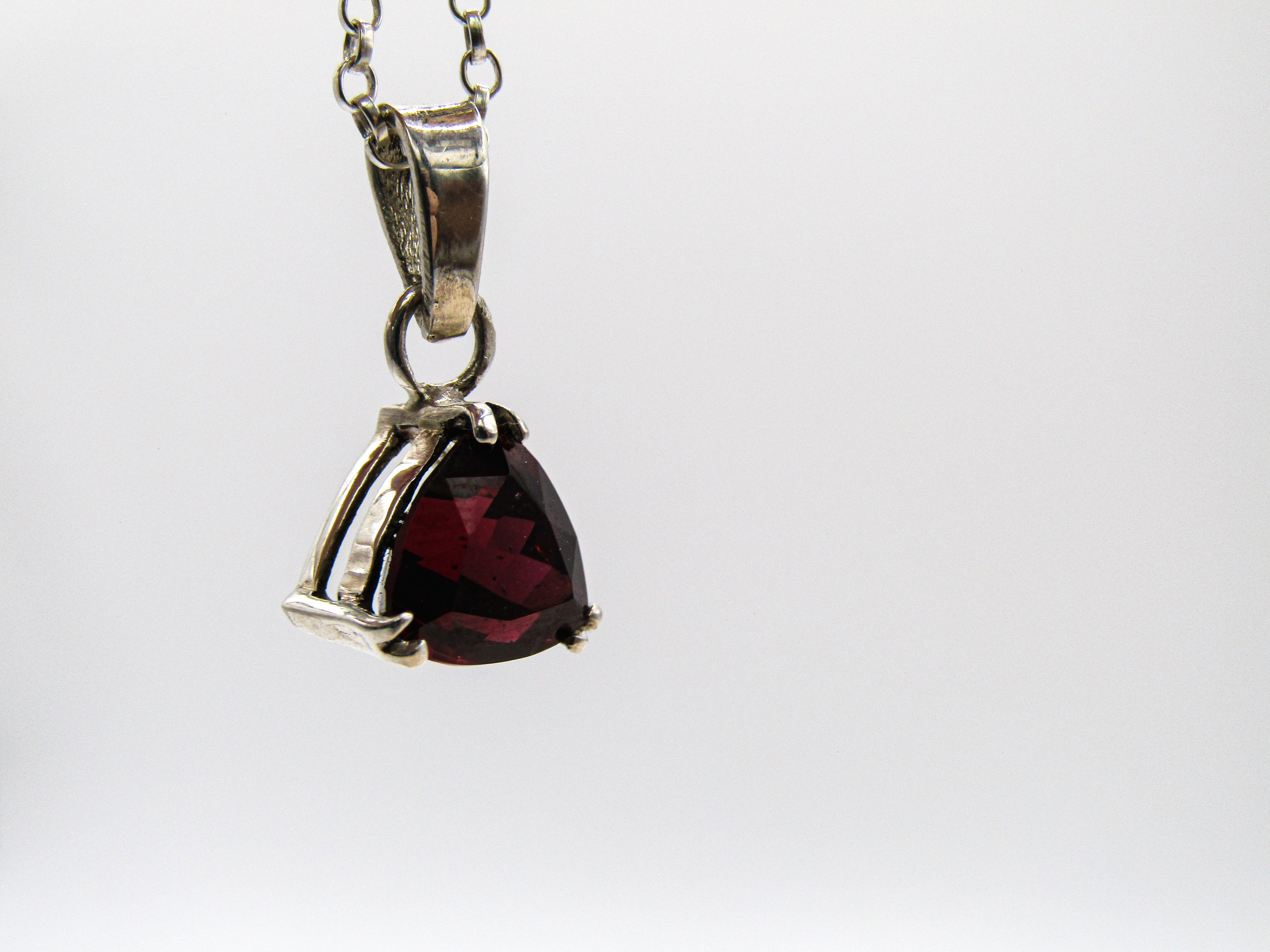 Silver pendant with a red gemstone on a white background