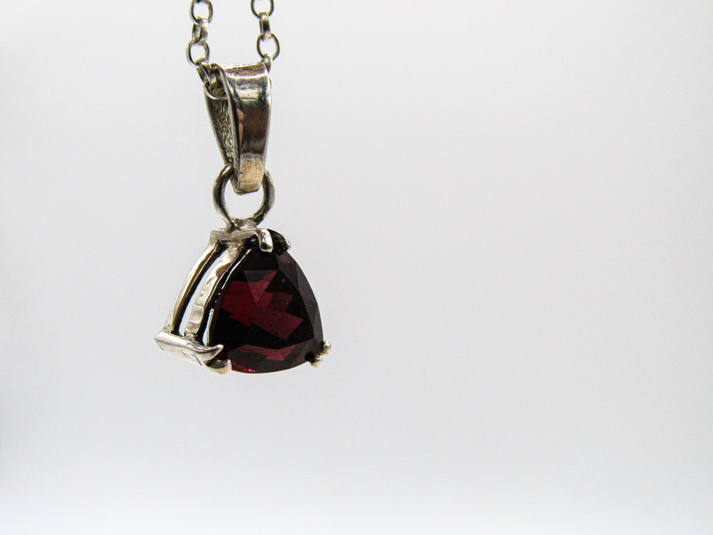 Silver pendant with a red gemstone on a white background