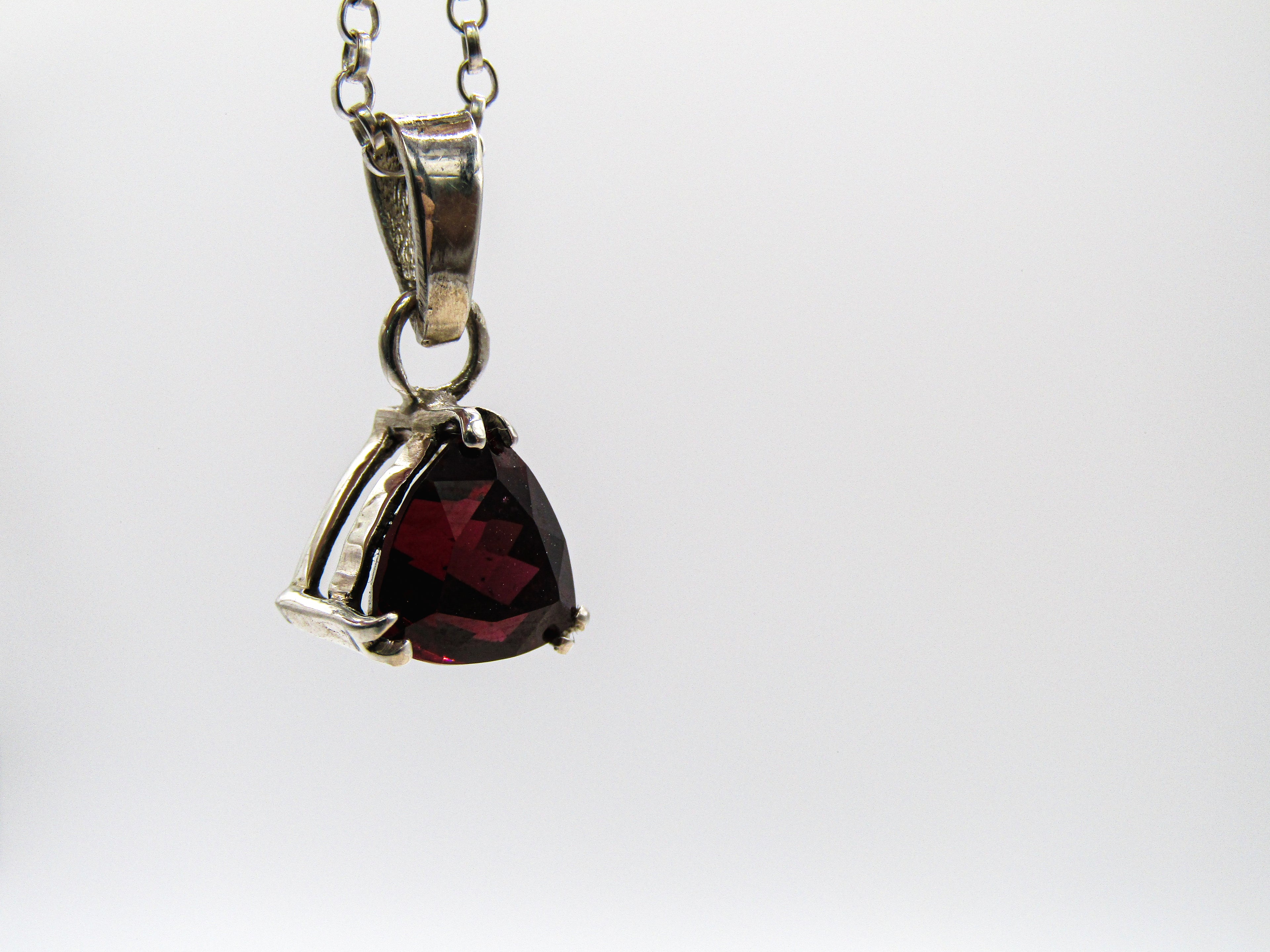 Silver pendant with a red gemstone on a white background