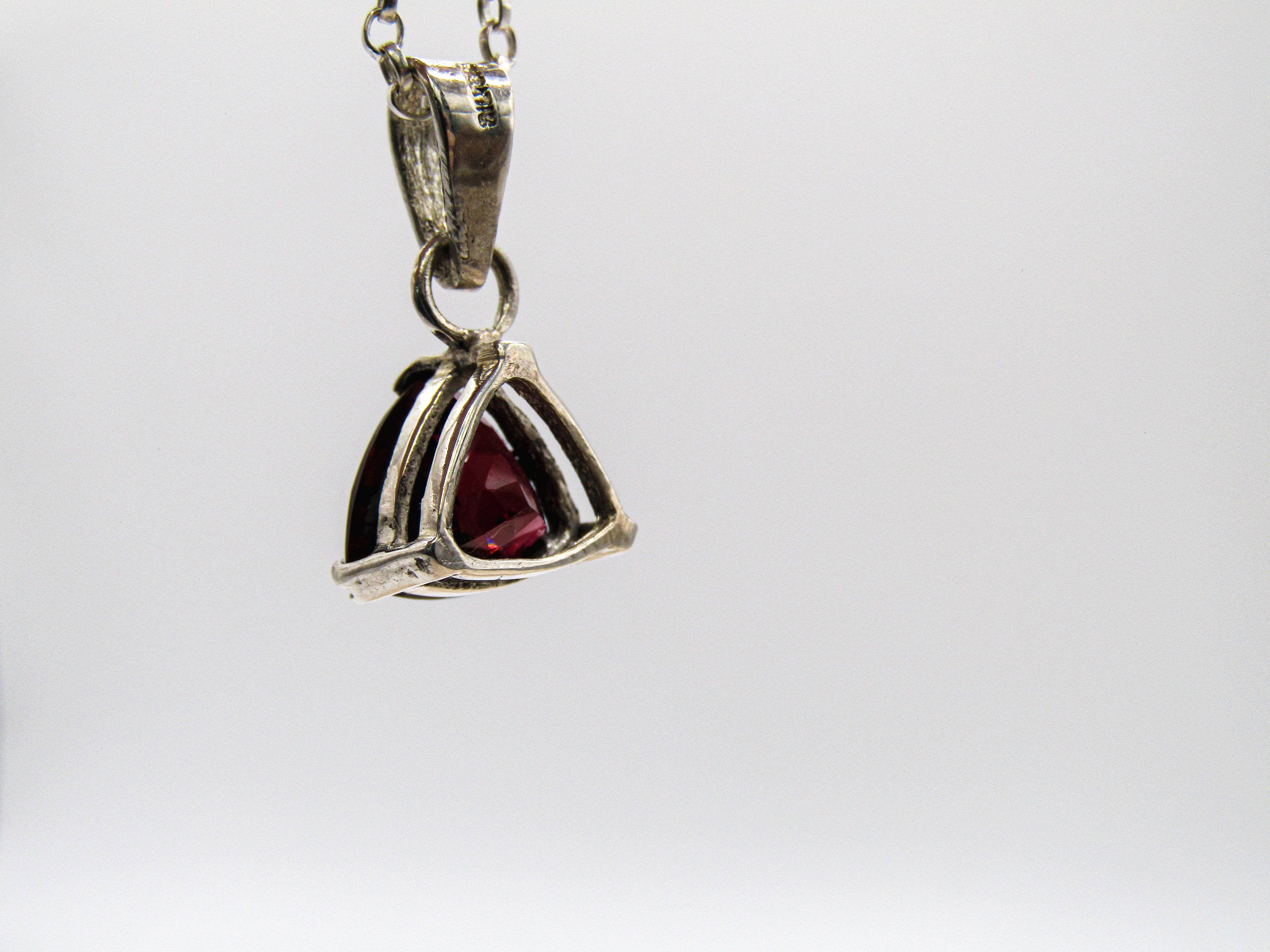 Silver pendant with a red gemstone on a white background