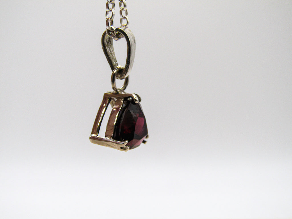 Silver pendant with a red gemstone on a white background