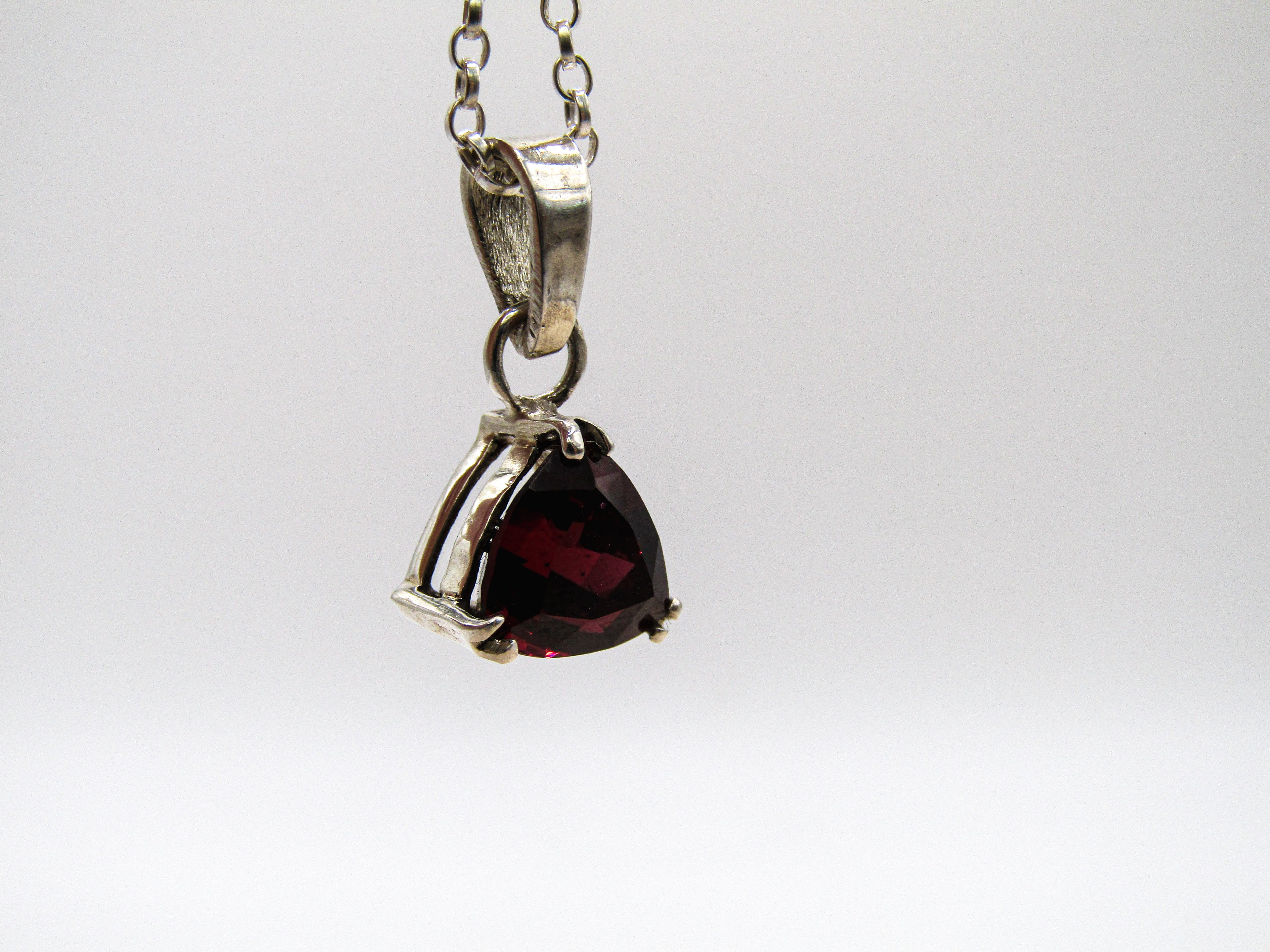 Silver pendant with a red gemstone on a white background