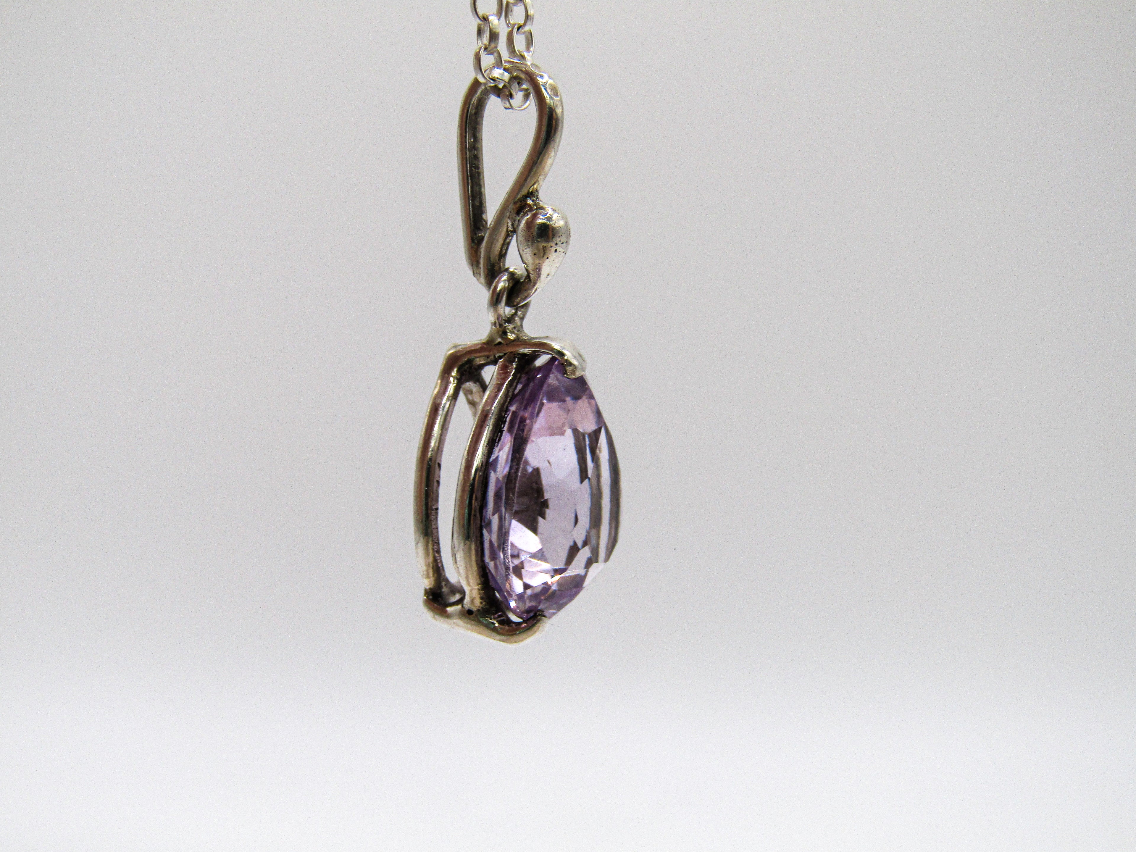 Purple gemstone pendant on a silver chain against a white background