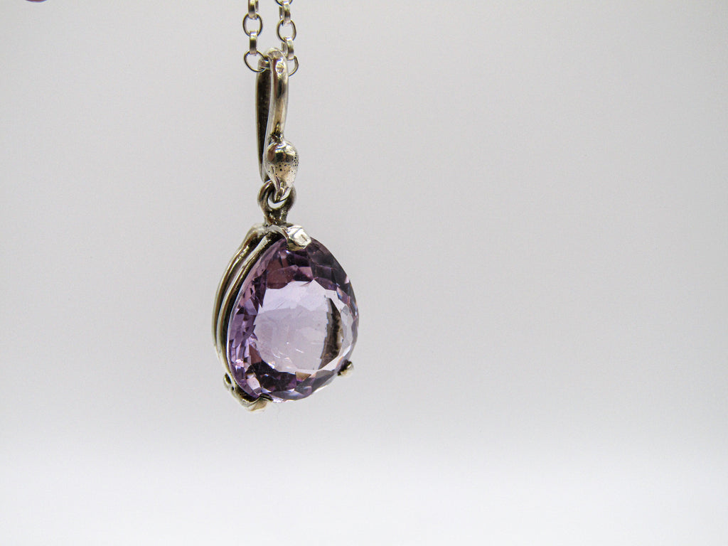 Purple teardrop pendant on a silver chain against a white background