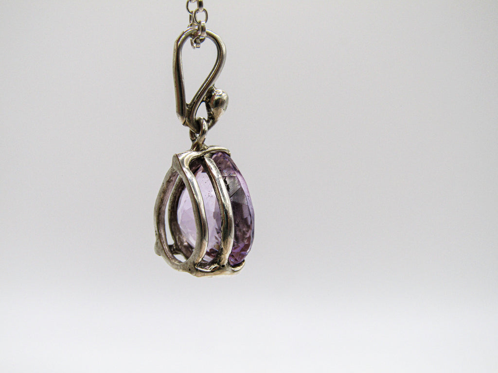 Silver pendant with a purple gemstone on a white background