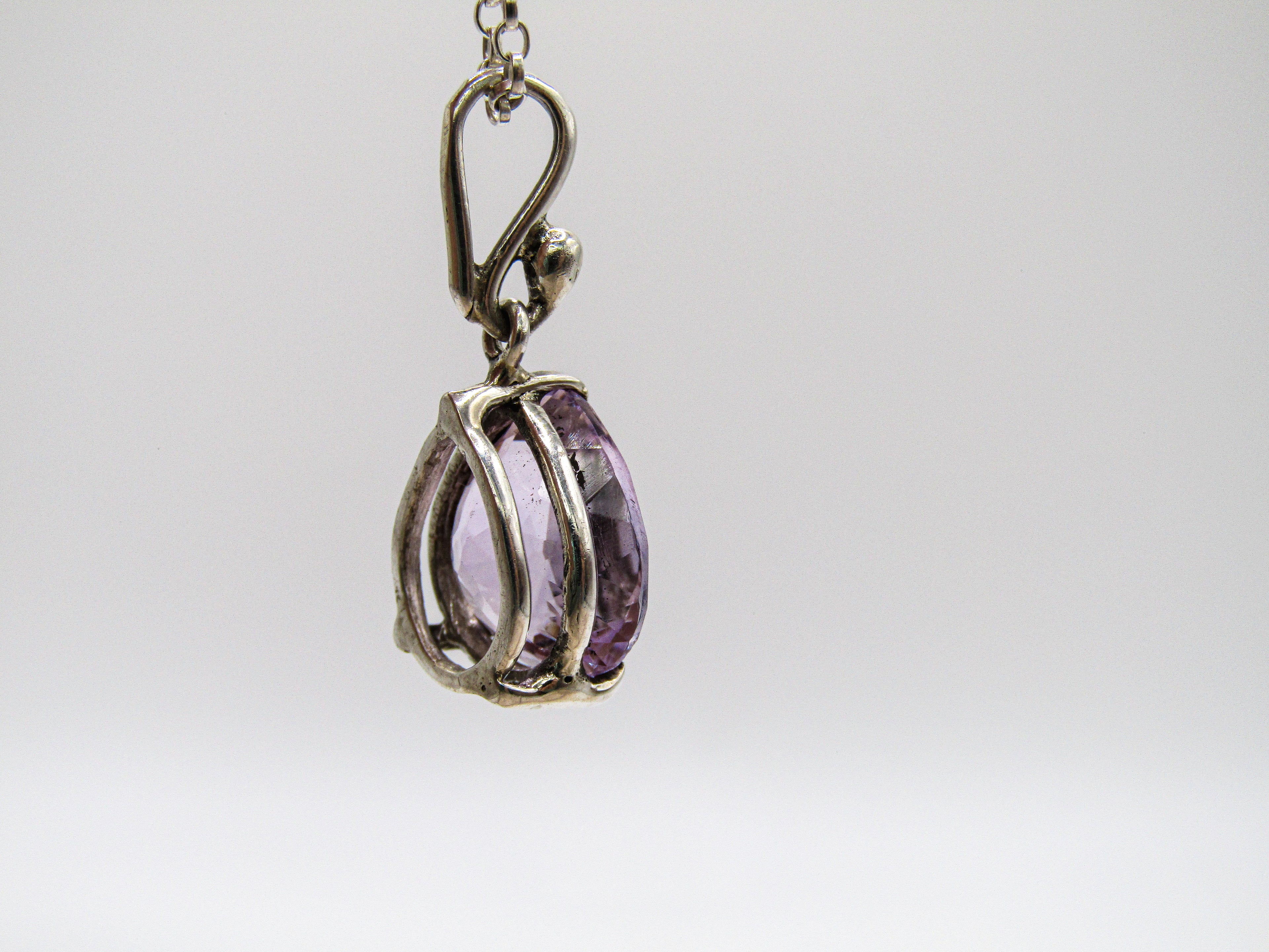 Silver pendant with a purple gemstone on a white background