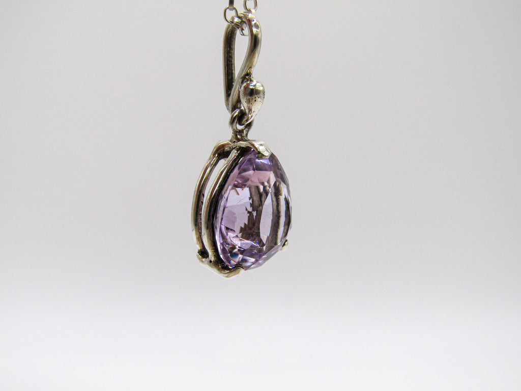Purple teardrop pendant on a chain against a white background