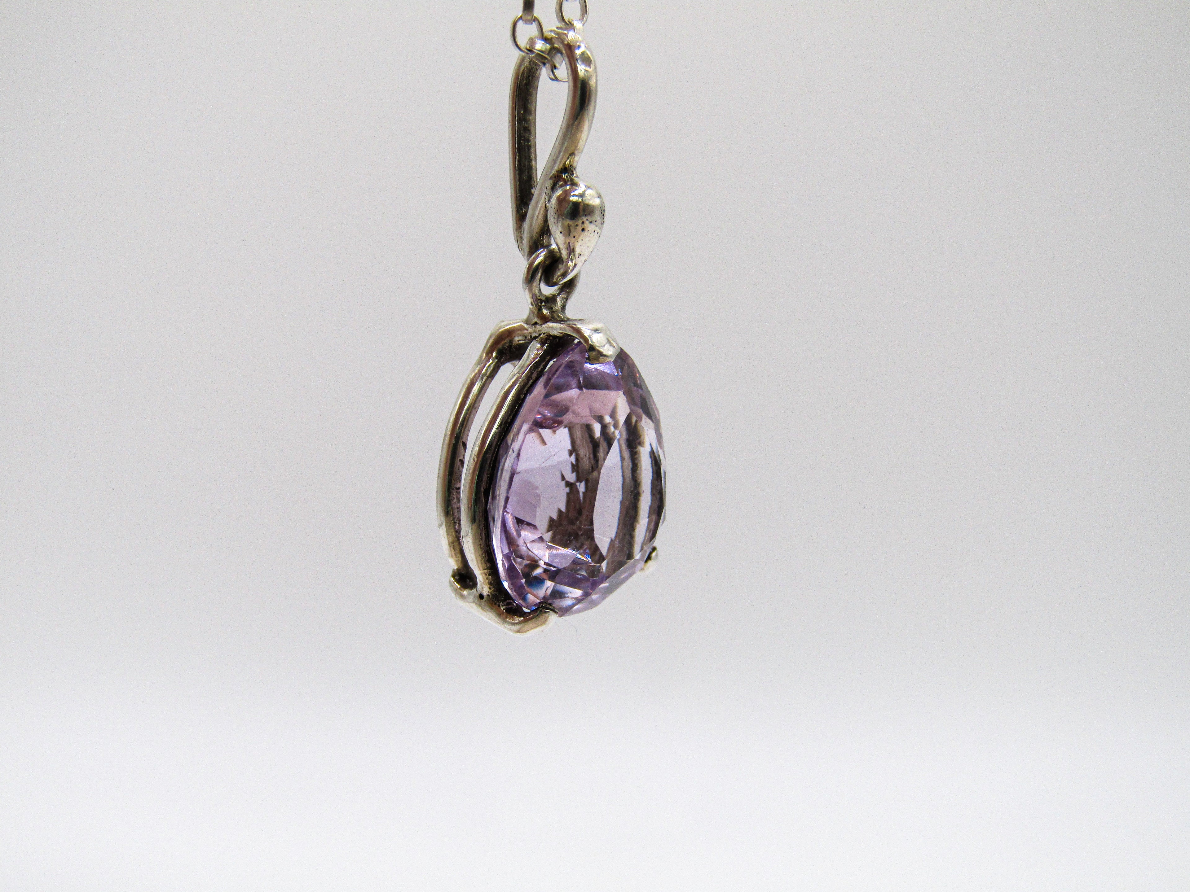 Purple teardrop pendant on a chain against a white background