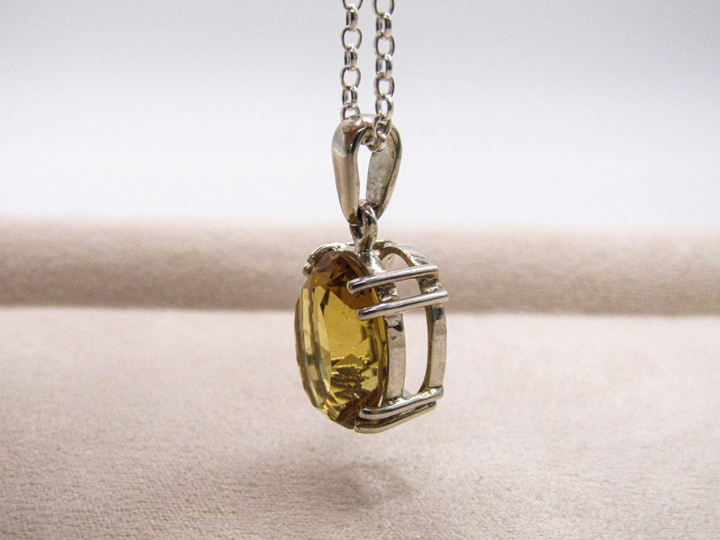 Silver pendant with a yellow gemstone on a white background