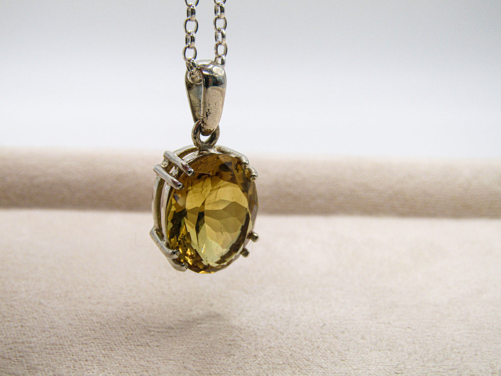 Gold pendant on a chain against a neutral background